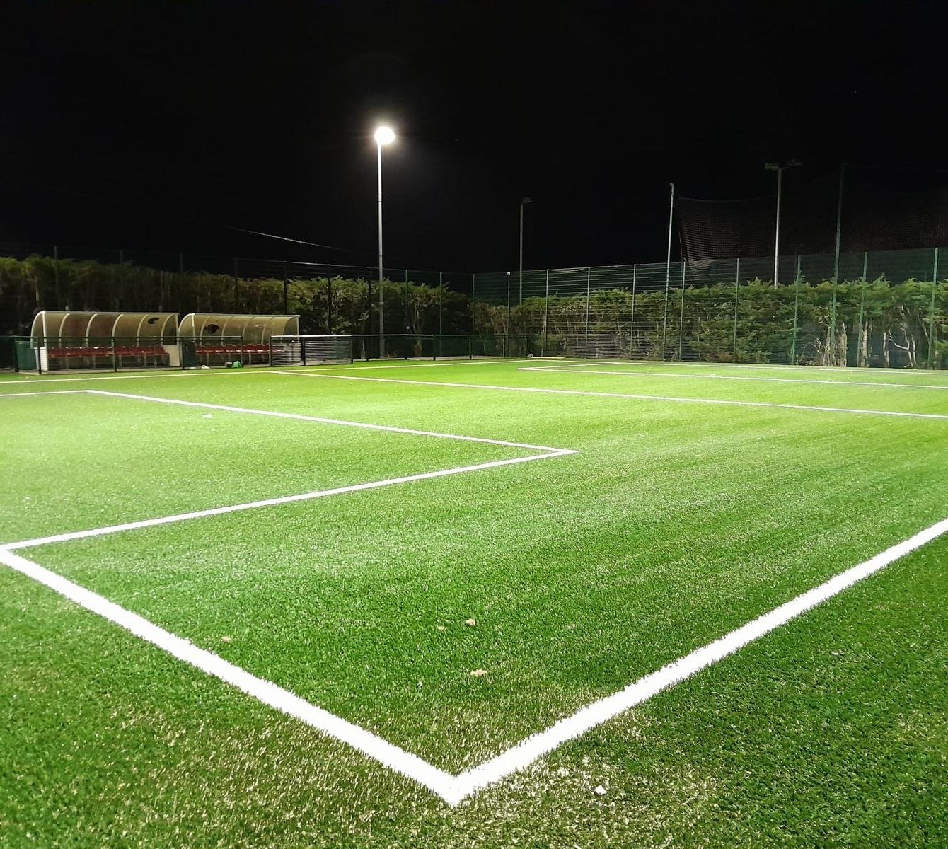 A floodlit artificial football pitch with crisp white line markings