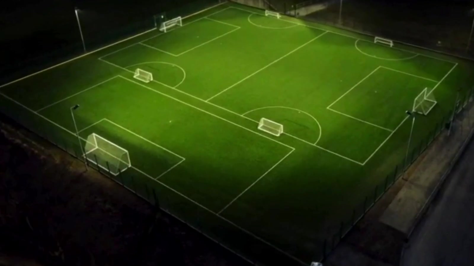A floodlit artificial pitch seen from above after a deep clean