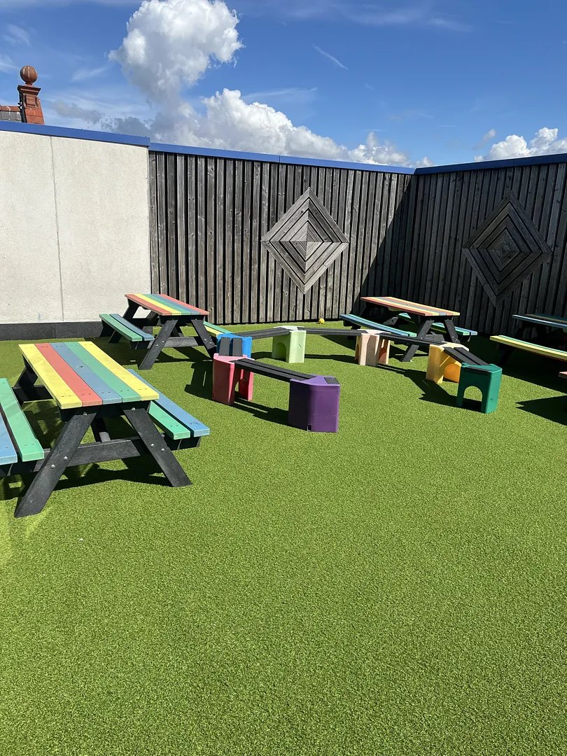 A school outdoor area on artificial grass with picnic benches