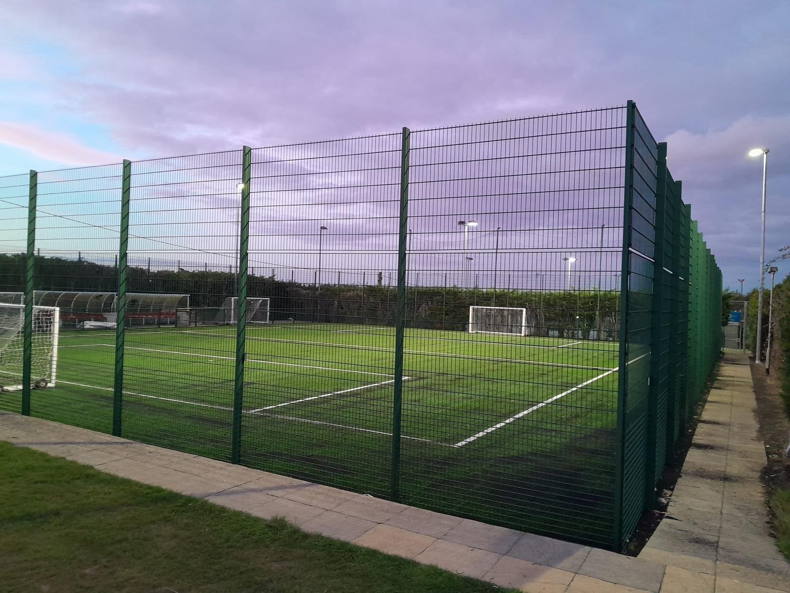 A fenced artificial pitch at dusk