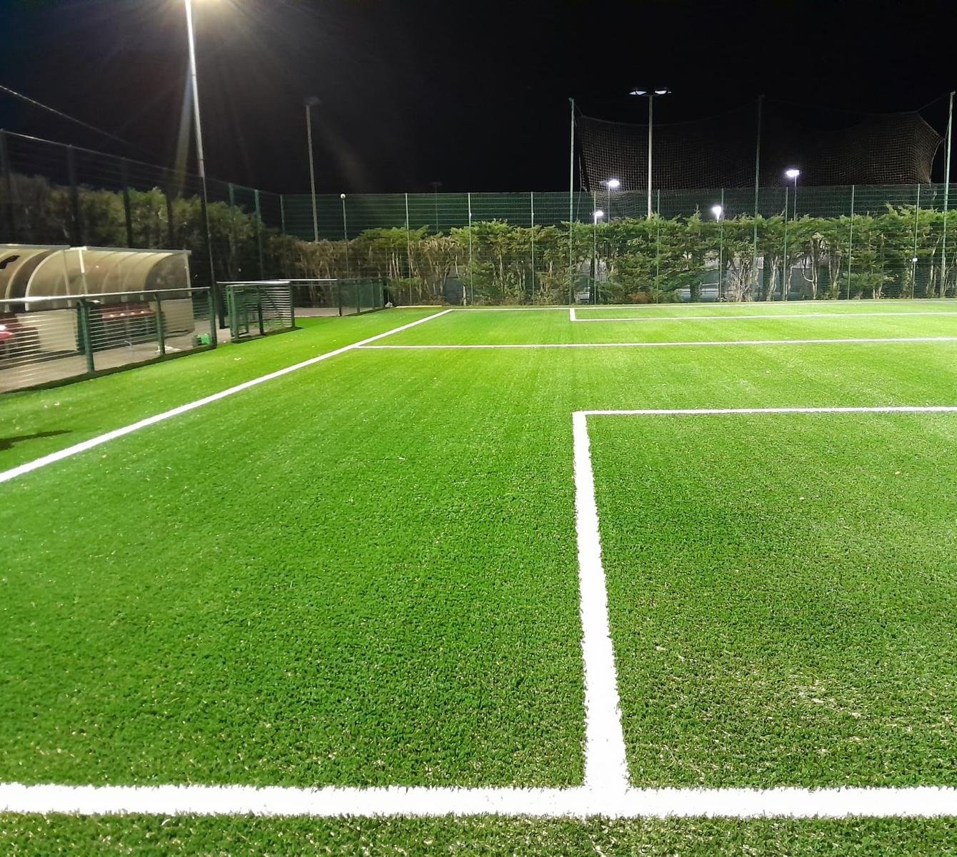 A floodlit artificial pitch with line markings